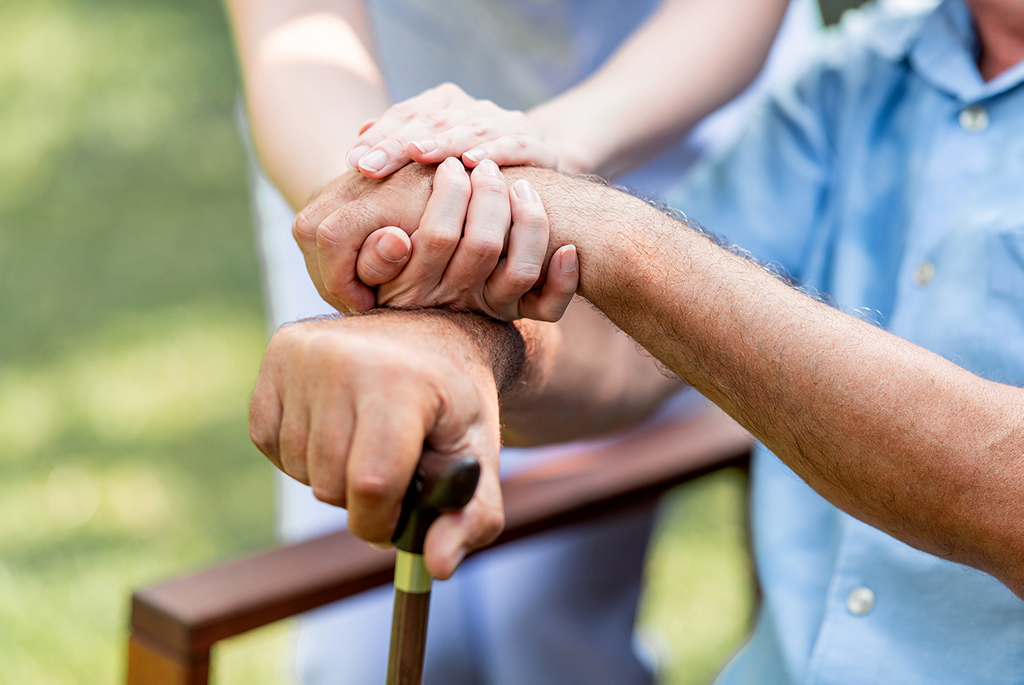 cna caregiver and senior holding hands closeup